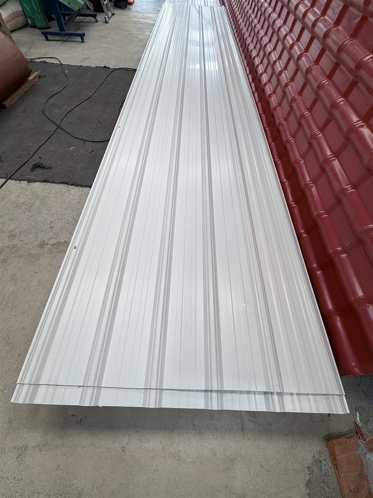 Detalle de una teja UPVC blanca junto a tejas tipo española